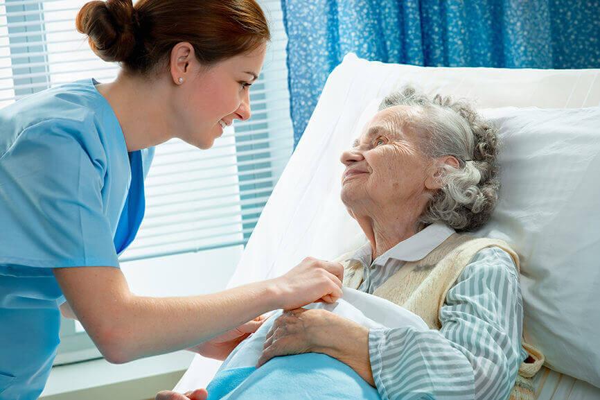 Nurse caring for elderly patient at bedside