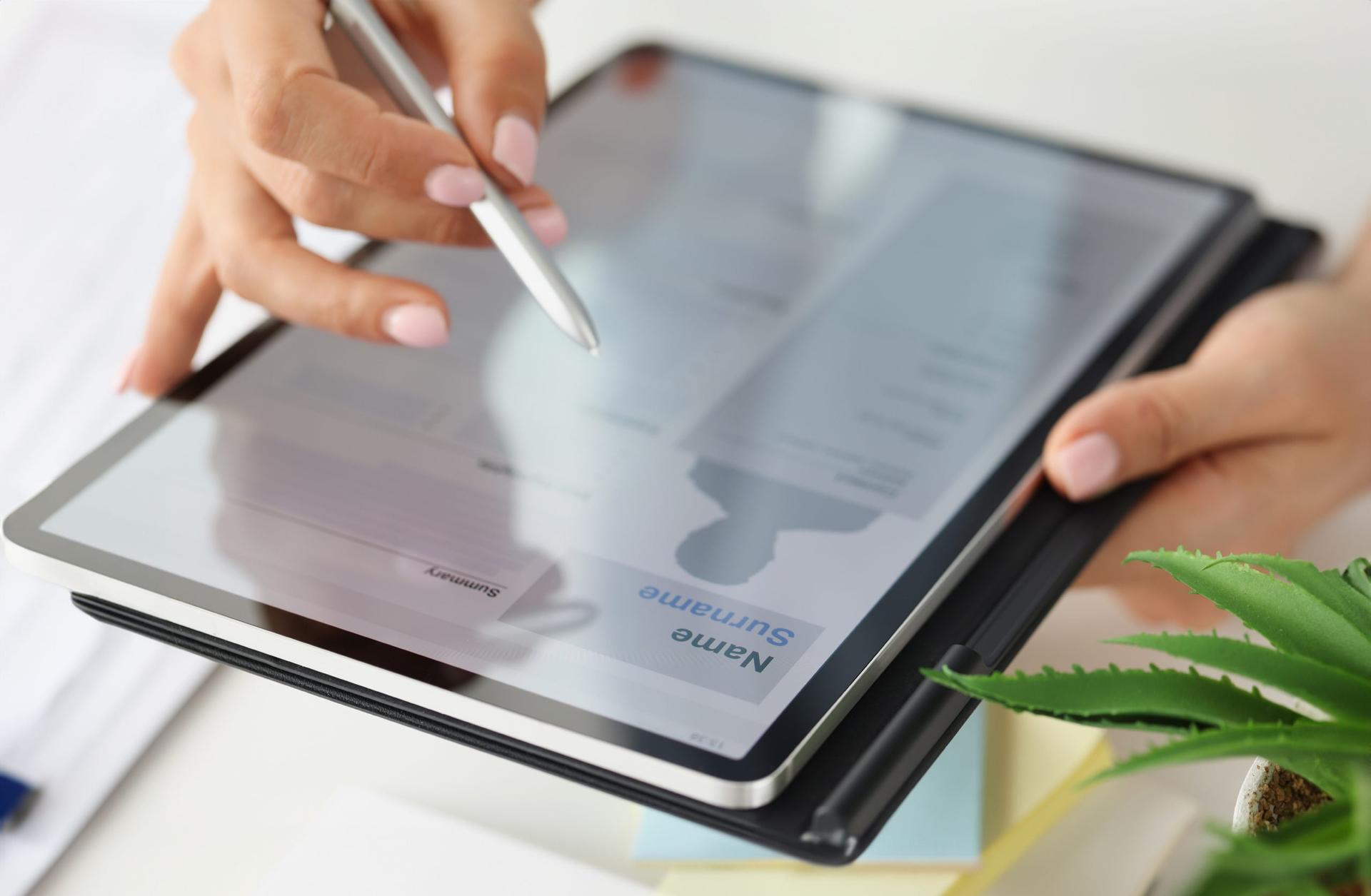 closeup of a woman holding an e-tablet and cursor while reviewing an electronic resume