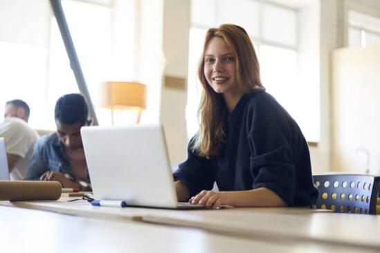 A professional writing a cover letter on their laptop while emphasizing their transferable skills.