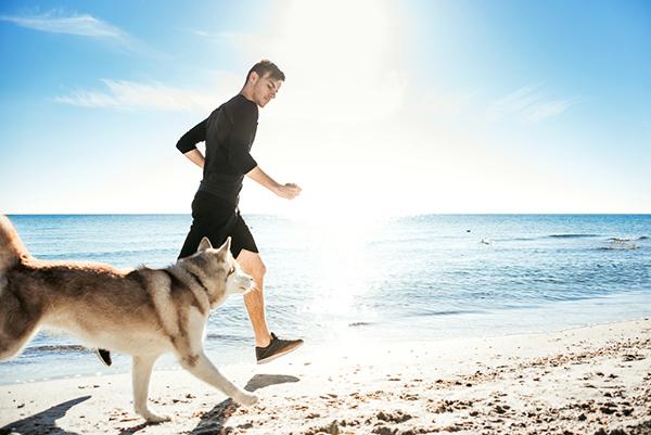 Man running on the beach with dog
