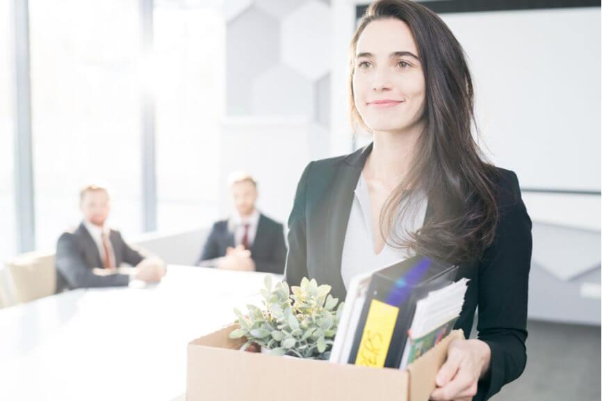 laid off employee smiles as she carries belongings out of office