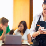 college-aged server writes order in front of studying students
