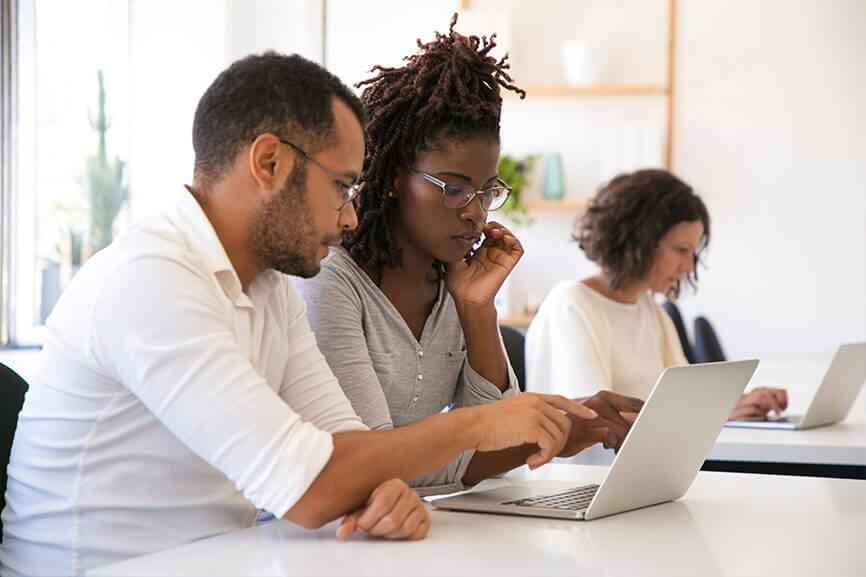 Male coworker showing something on female coworker's laptop